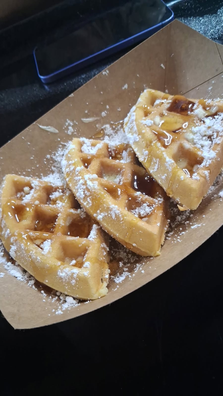 Waffles dusted with powdered sugar and syrup at GKL Sunday brunch