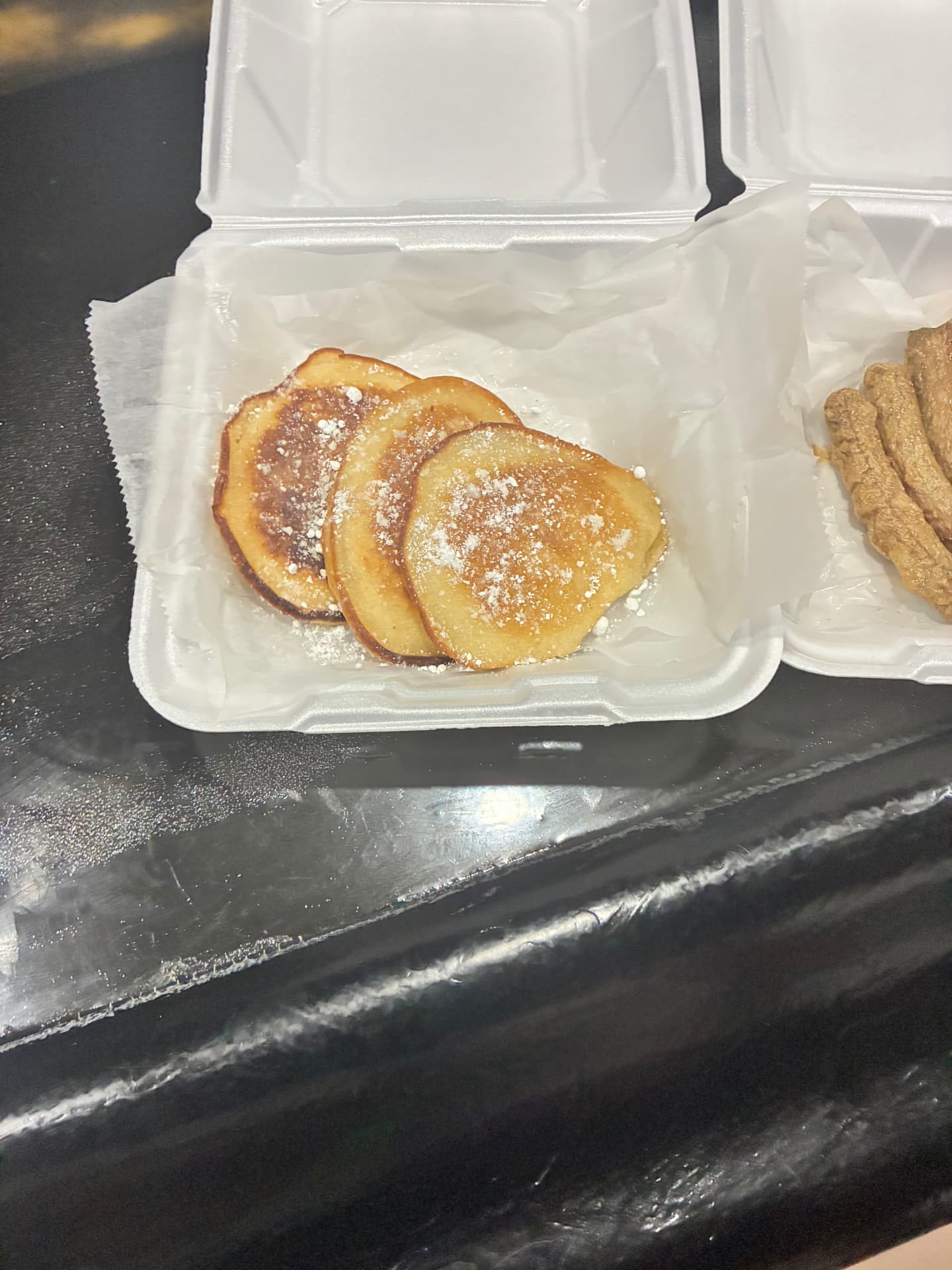 Pancakes with powdered sugar in a takeout container at GKL